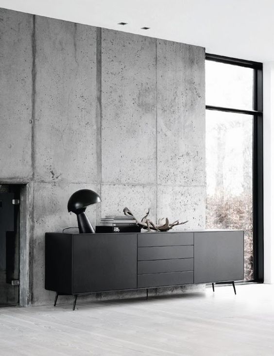 unfinished concrete wall in a living room and black furniture in front of it