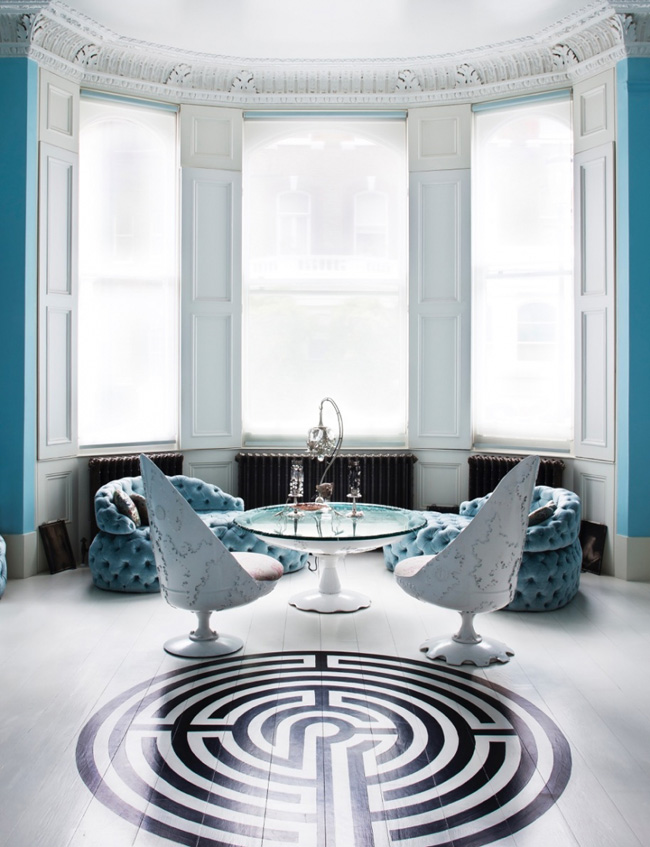 geo living room Matching blue chairs are placed by the large windows and there's a cool geo pattern on the living room's floor
