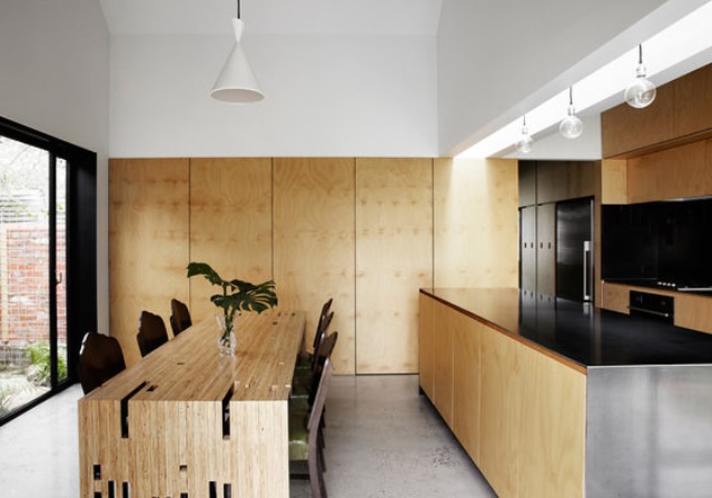 The kitchen is clad with light-colored wooden panels and the unusual architectural countertop is usedas a dining table