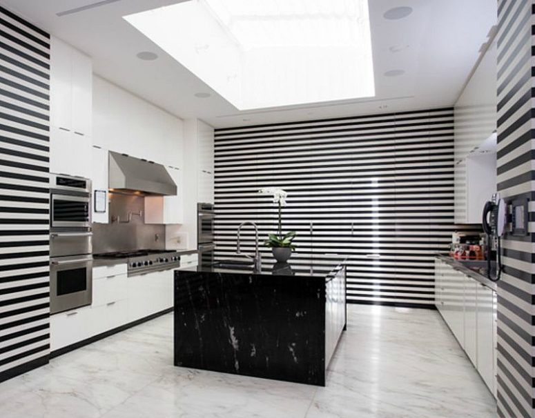 The kitchen is done in black and white stripes, with white drawers and a black marble kitchen island