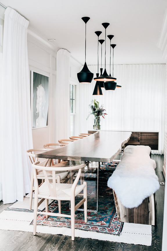 textural wooden table This is a dining zone with a raw-wood edge dining table with acrylic legs, a fur covered bench and lots of lights