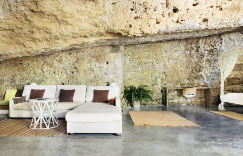 Open living area surrounded by natural stone fomations, with various textiles to add a cozy feeling