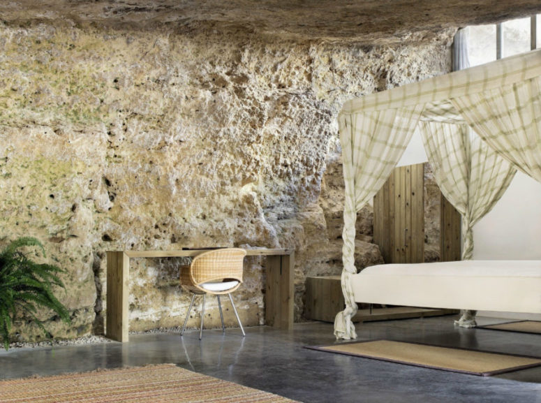 Canopy bed with complementary furniture made of natural wood stands right next to the living room as the layout is open