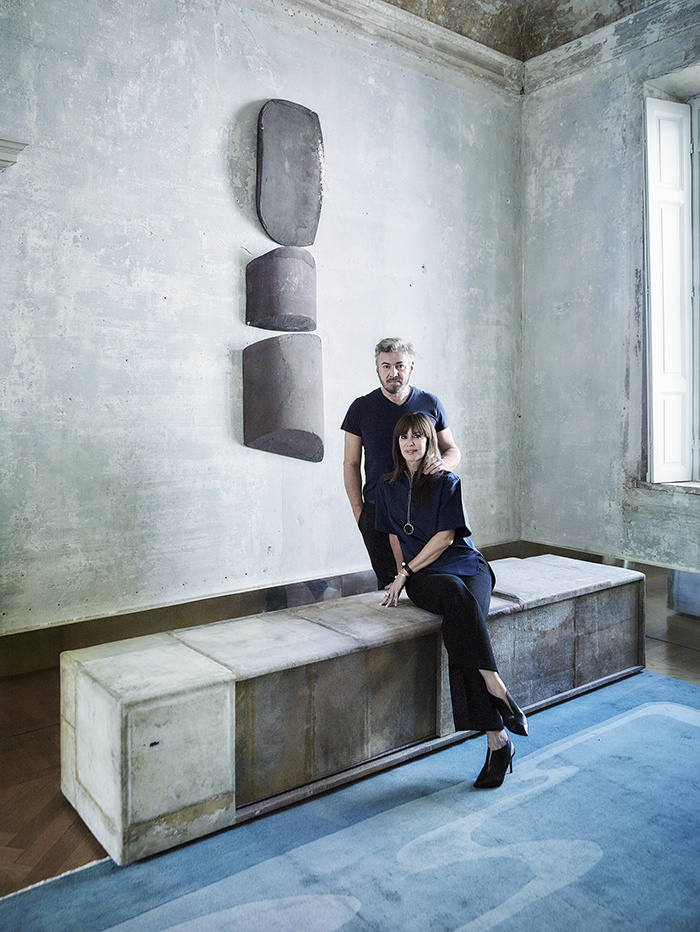 The owners in the living room with a cabinet of recycled materials, which is the first creation of the designer