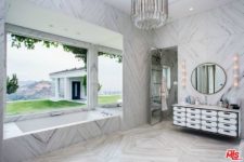 11 The master bathroom is clad with light-colored marble, the design is totally glam