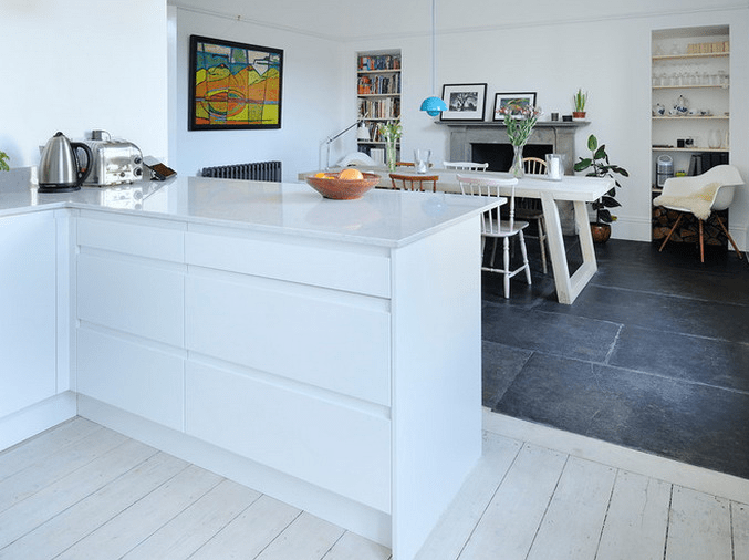 whitewashed wooden floors in the serene kitchen area and black tiles in the dining area