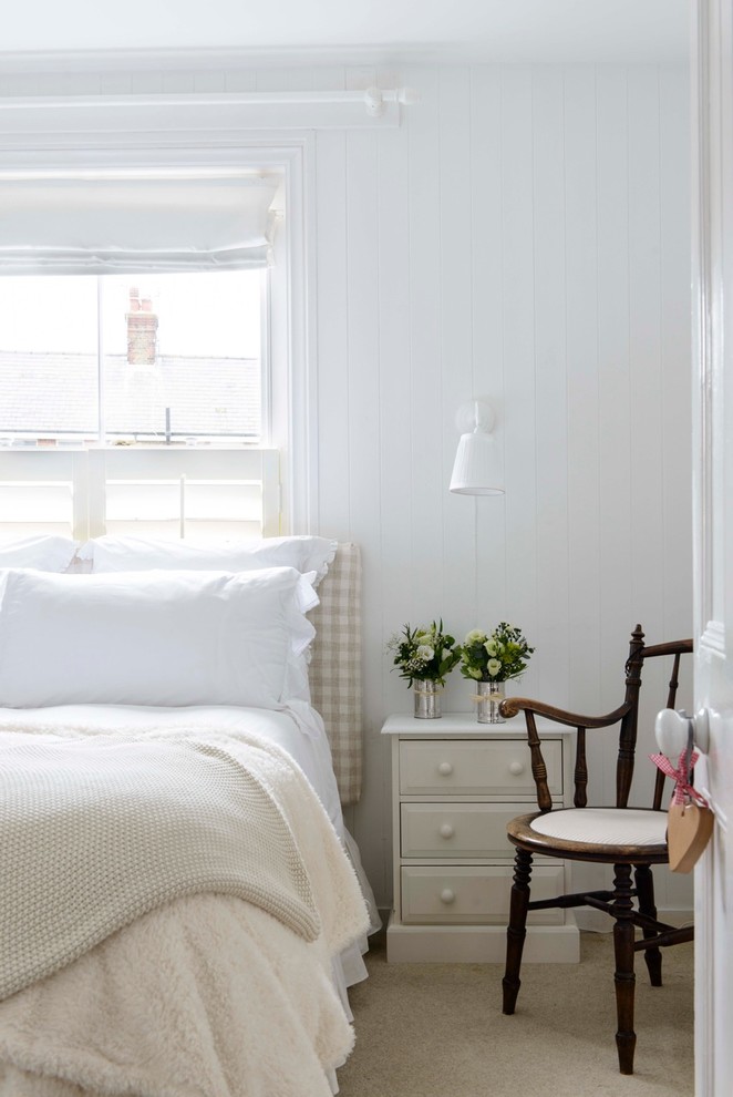 An airy coastal-inspired bedroom with taupe carpet flooring and whitewashed walls. This simple color scheme is a great way to create a non-minimalist yet neutral interior. (Whitstable Island Interiors)