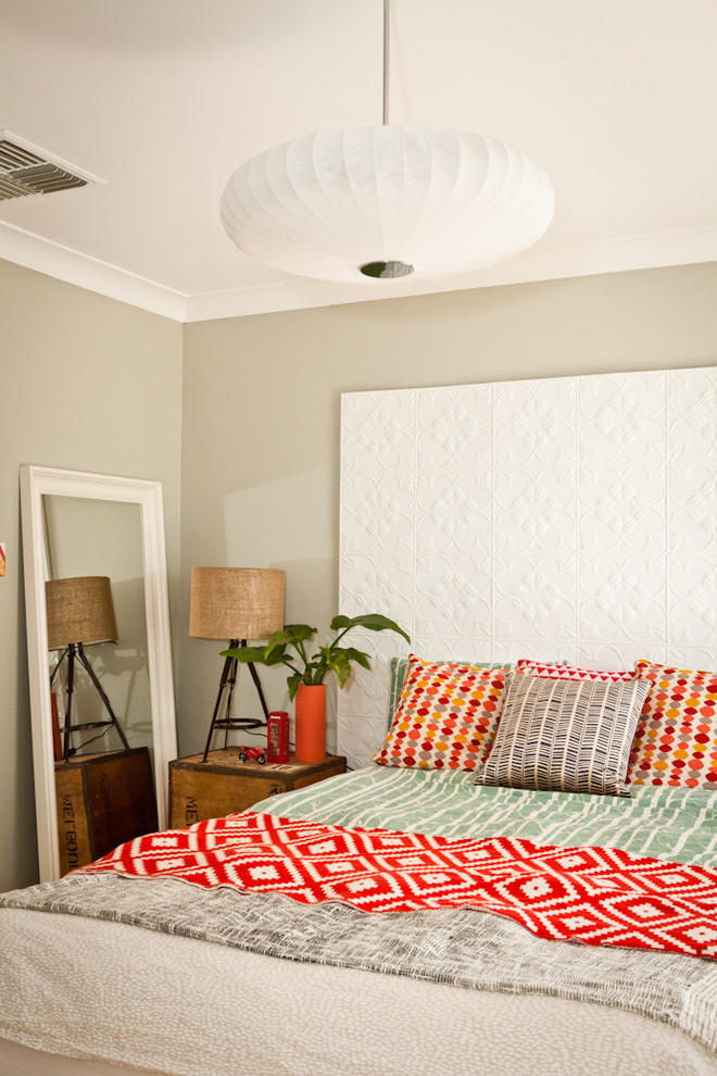 This small light taupe bedroom features a bunch of colorful touches to make it look more interesting. A mix of bright oranges and reds is a great addition to a too neutral interior. (Twinkle and Whistle)