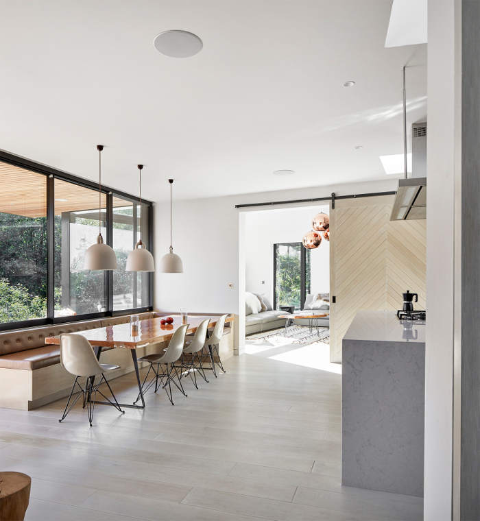 The kitchen and dining space are united into one room with adorable views and a sleek orange table as a statement piece
