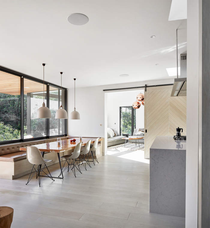 The kitchen and dining space are united into one room with adorable views and a sleek orange table as a statement piece The kitchen and dining space are united into one room with adorable views and a sleek orange table as a statement piece