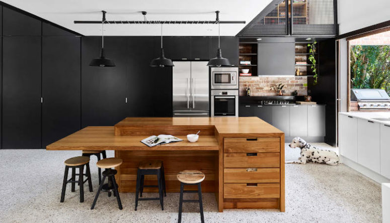 The kitchen is a modern sleek one, all the handles hidden and done in black, with a cool sculptural kitchen island