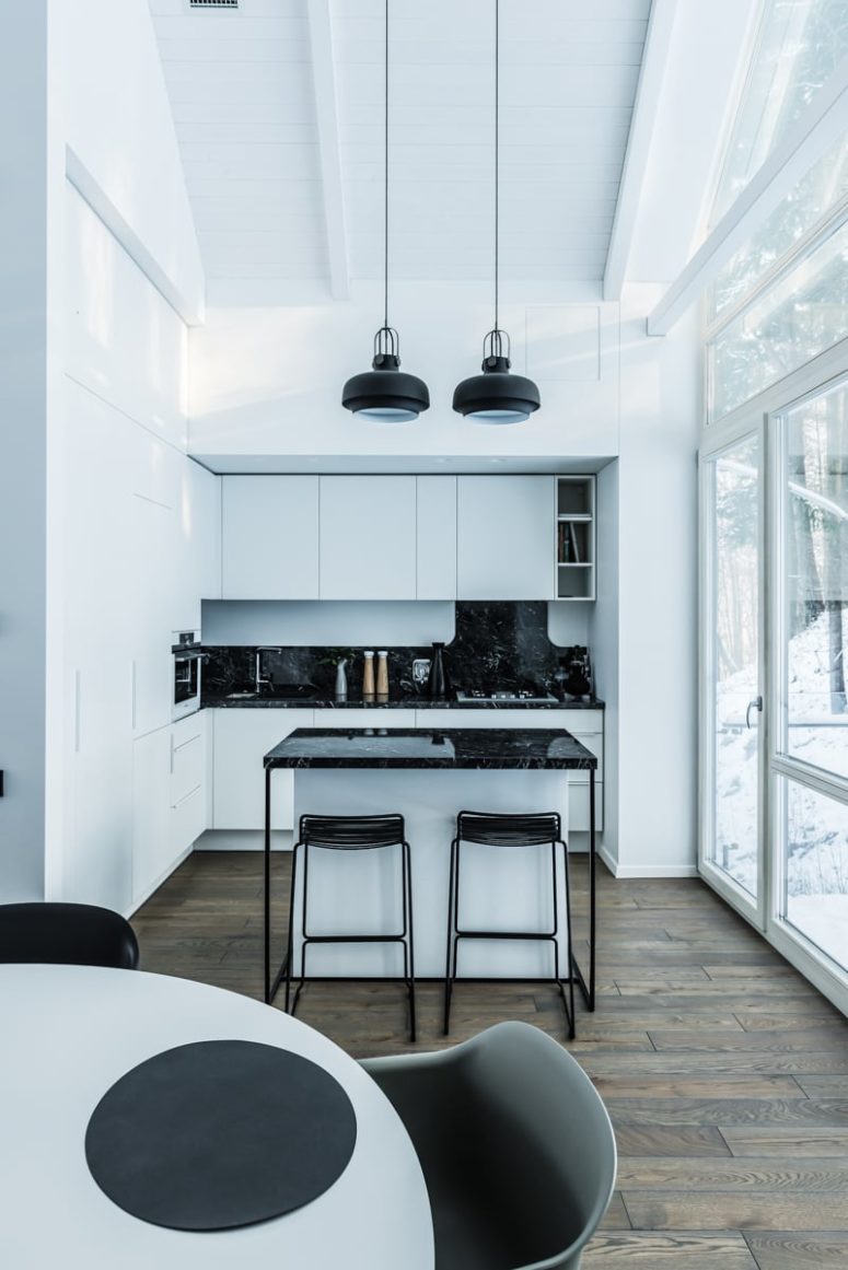 The kitchen is a small nook decorated in white and black marble, it's absolutely sleek and there are no handles visible