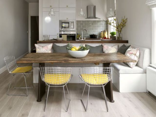 modern white sleek kitchen with grey tiles and a dining space with metal wire chairs grey pillows to echo