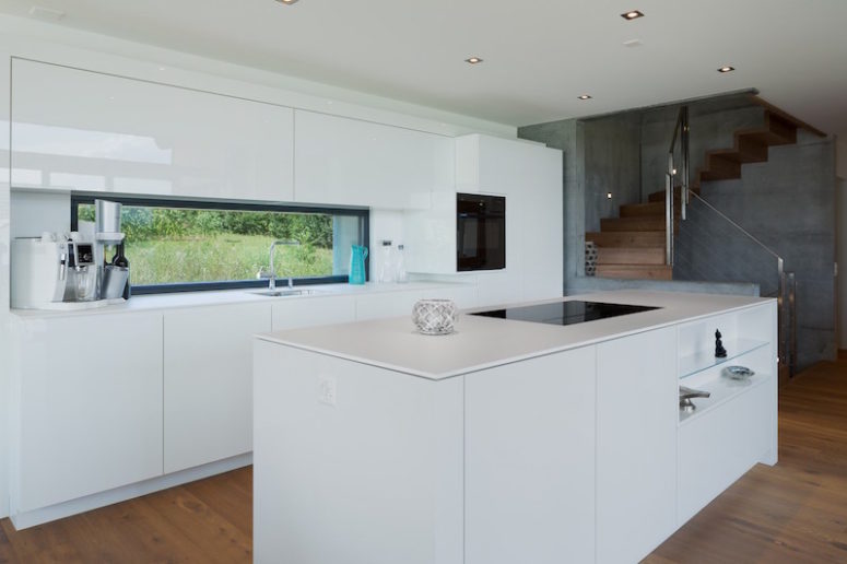 The kitchen is done in white, everything possible is hidden for a sleek look and there's a window instead of a backsplash The kitchen is done in white, everything possible is hidden for a sleek look and there's a window instead of a backsplash