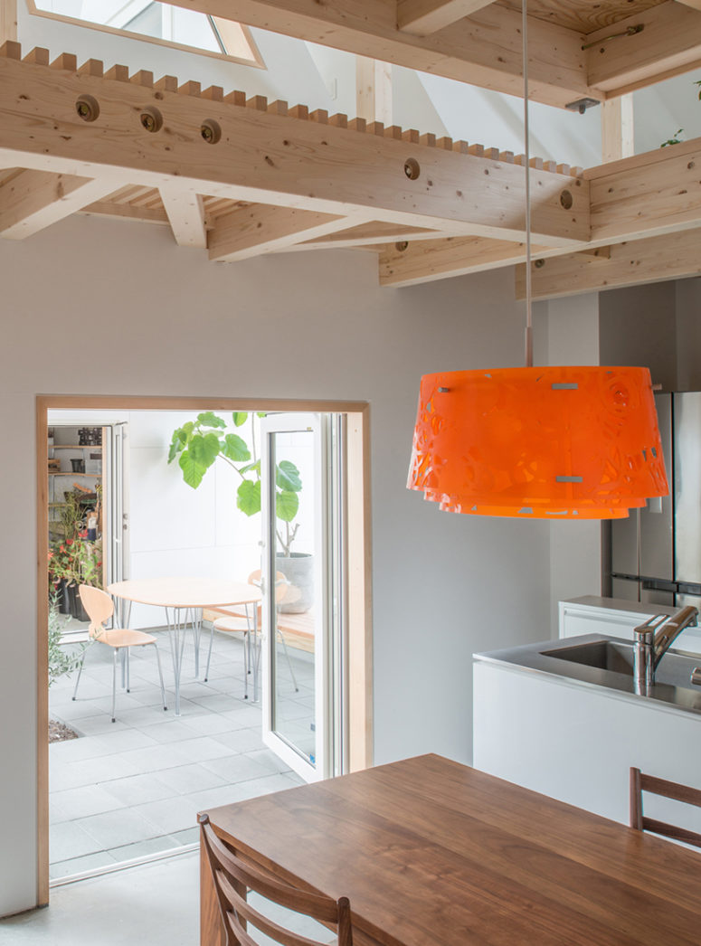 the kitchen is minimalist, with white cabinets, stainless steel surfaces and a warm woods, there's an eye-catchy bold pendant lamp