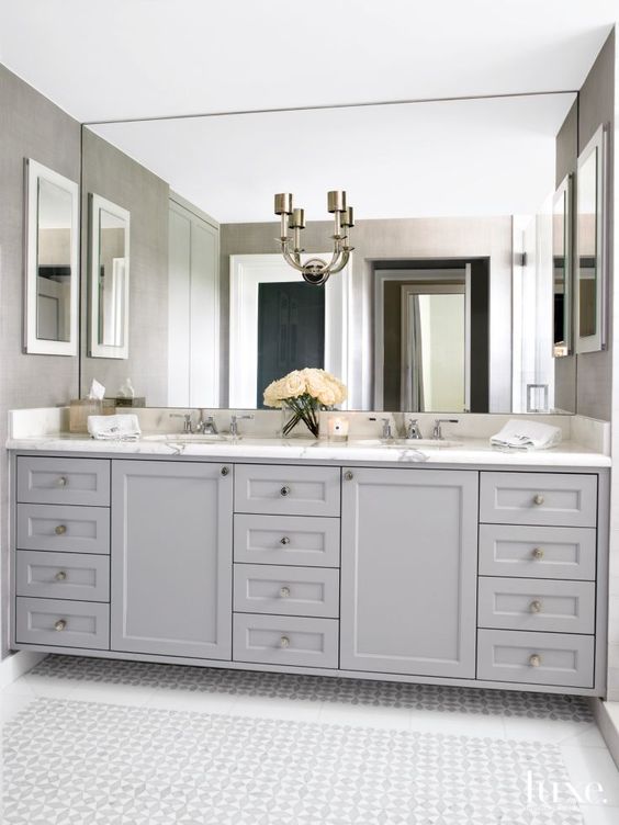 traditional grey cabinetry with a marble counter and a giant mirror up to the ceiling