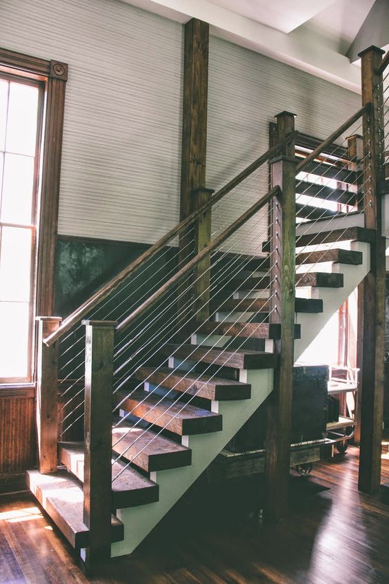 dark rustic wooden staircase with cable railing has a rough look