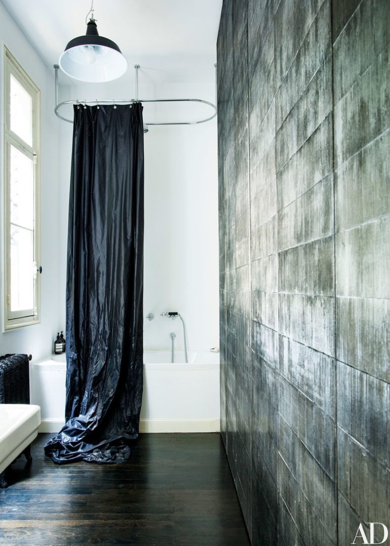 The bathroom features a unique wall and a black curtain for a white bathtub, looks very fashionable