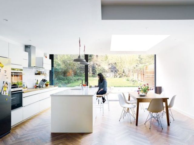 light-filled kitchen in white with a large kitchen island and dinign area with mid-century modern furniture