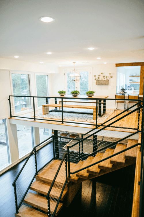 light and warm-colored wooden staircase with black metal and neutral cable railing