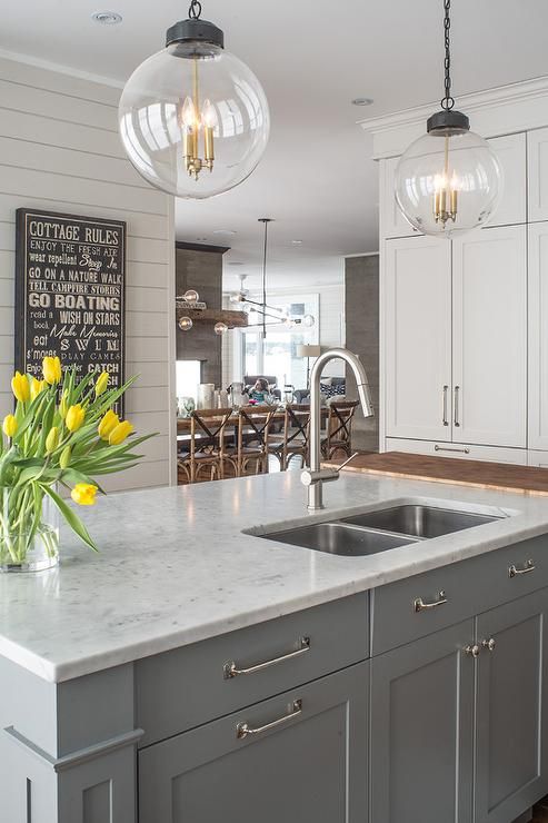 gray kitchen island topped with white quartz fitted with a stainless steel dual sink