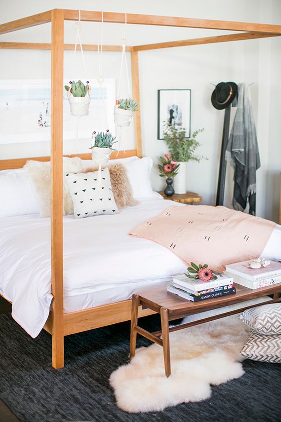 sweet girlish bedroom in blush with a light-colroed warm wood bed and planters hanging from the frame