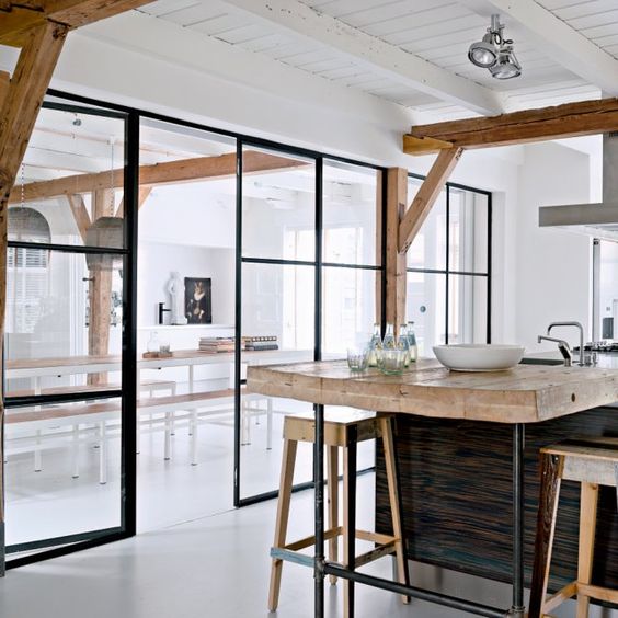 the kitchen and dining room divided with a framed glass wall with a door