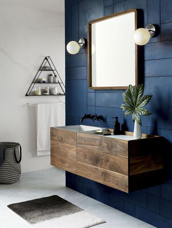 dark wood bathroom cabinet with drawers on a contrasting navy wall