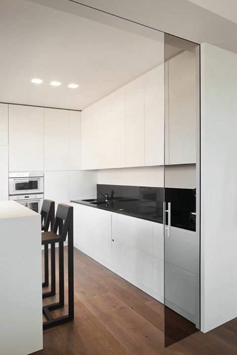 minimalist white kitchen separated with dark glass sliding doors