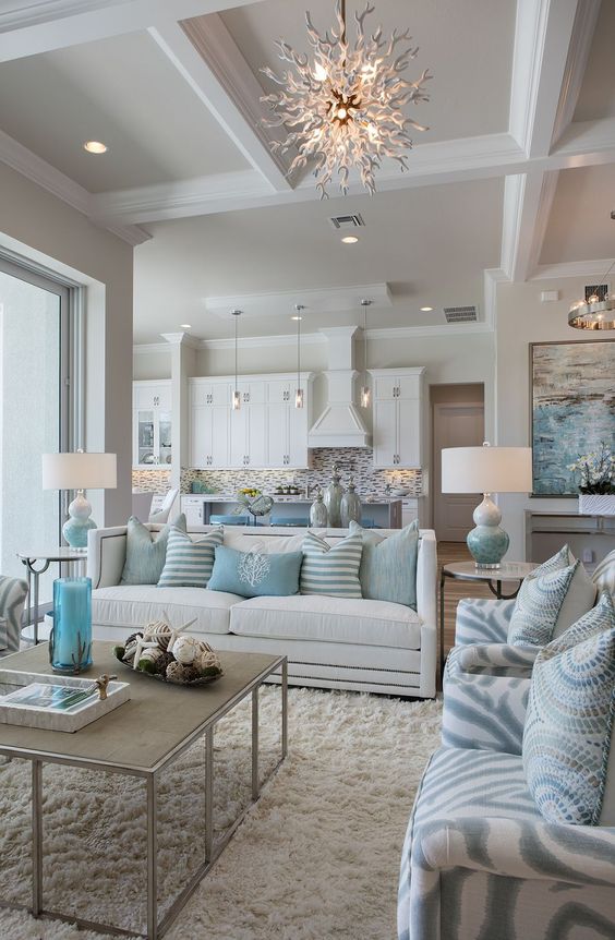 the kitchen is done all-white, while the living room shows various colors of blue and lots of textures