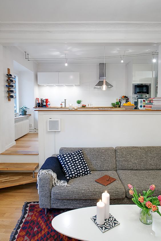 modern white kitchen with lots of light and a living room with cozy textiles and upholstery