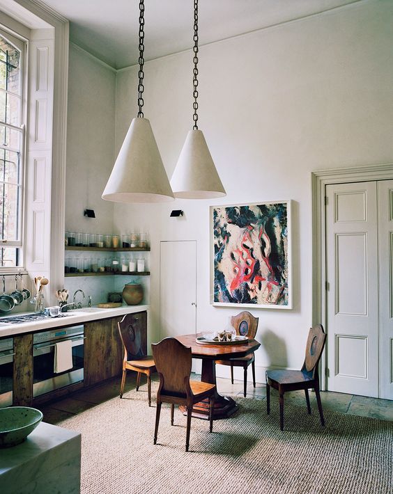 The kitchen features rustic furniture, a bold artwork and industrial-inspired pendant lamps, all of that looks harmonious here