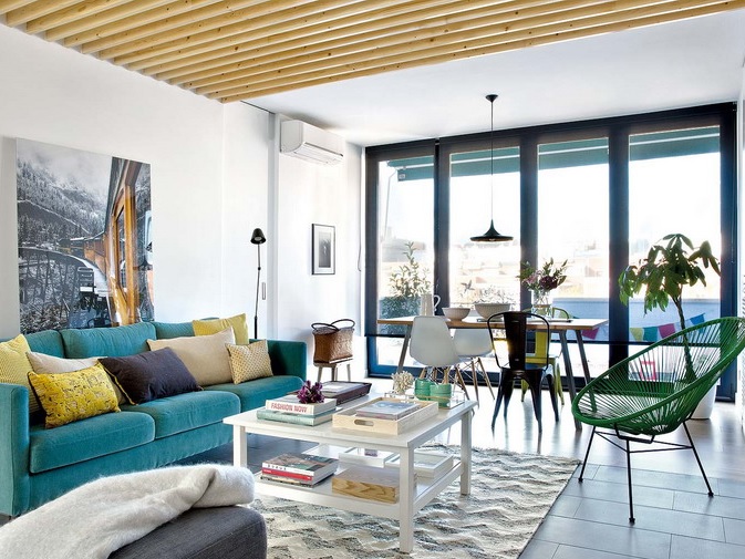 The living room features a turquoise sofa, wooden beams on the ceiling and walls, they make the room cozier