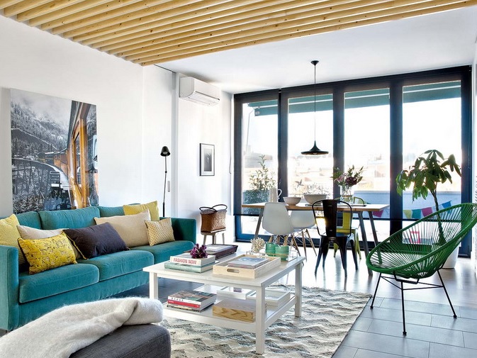 The living room features a turquoise sofa, wooden beams on the ceiling and walls, they make the room cozier The living room features a turquoise sofa, wooden beams on the ceiling and walls, they make the room cozier