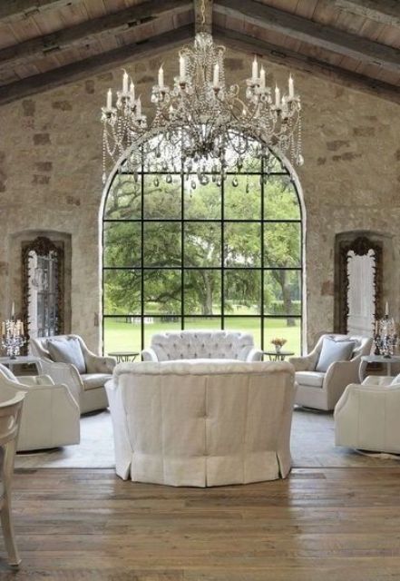 a vintage living room with white fabric furniture and an oversized vintage chandelier with hanging crystals, candles and bead garlands