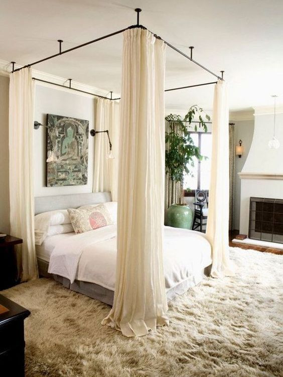 light grey upholstered bed and curtains around the bed to make it comfy and private