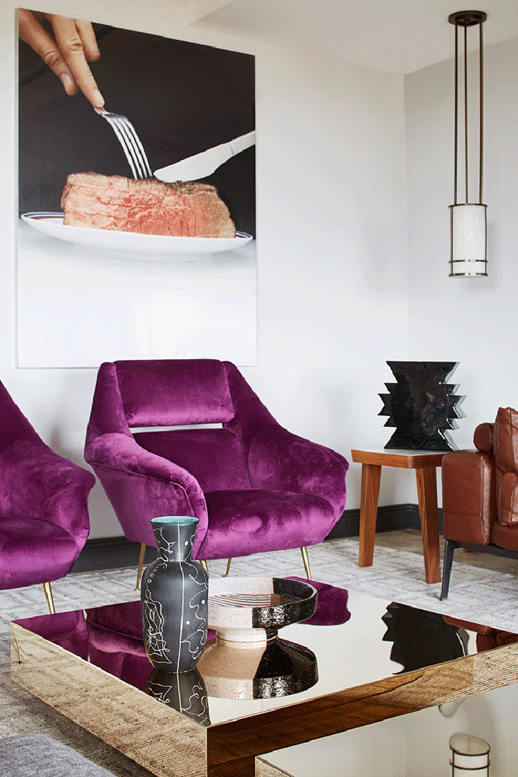 oversized photo wall Purple upholstered chairs, gold mirror tables and creative oversized photos on the wall make the space unique
