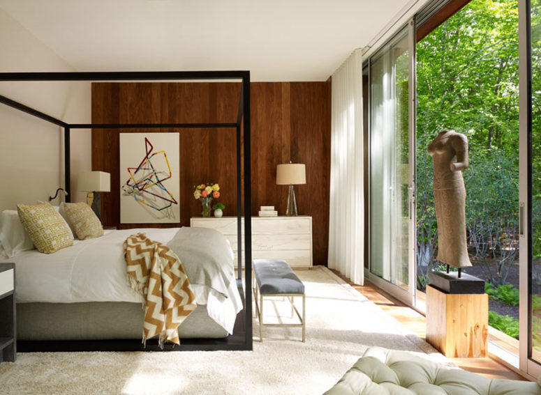 The master bedroom features a large framed bed, a geometric wall art and an antique sculpture