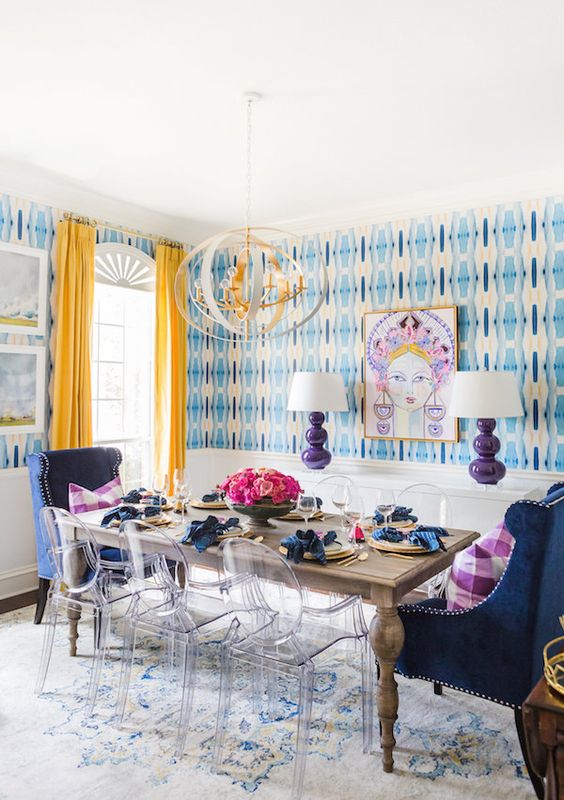 a simple wooden table is accentuated with sheer chairs and blue upholstered chairs