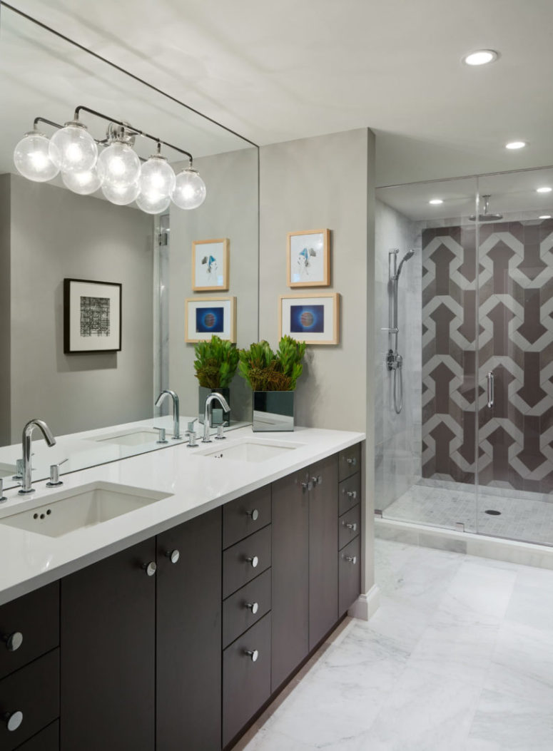 The bathroom is rather light-colored, with a buld lighting fixture and marble tiles on the floor, and I love geometric pattern tiles