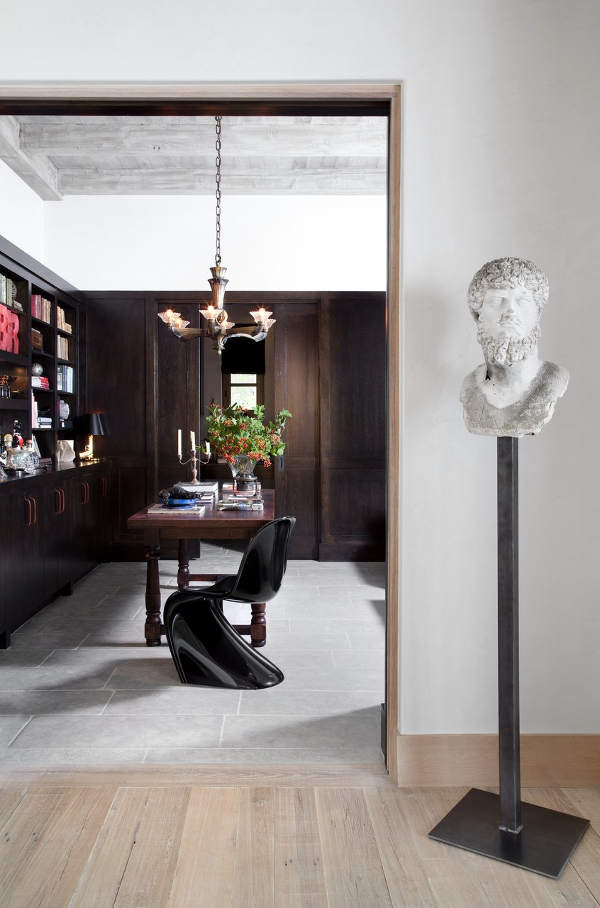 The home office is clad with dark wood, there are traditional shelves and a desk but a modern twisted chair The home office is clad with dark wood, there are traditional shelves and a desk but a modern twisted chair