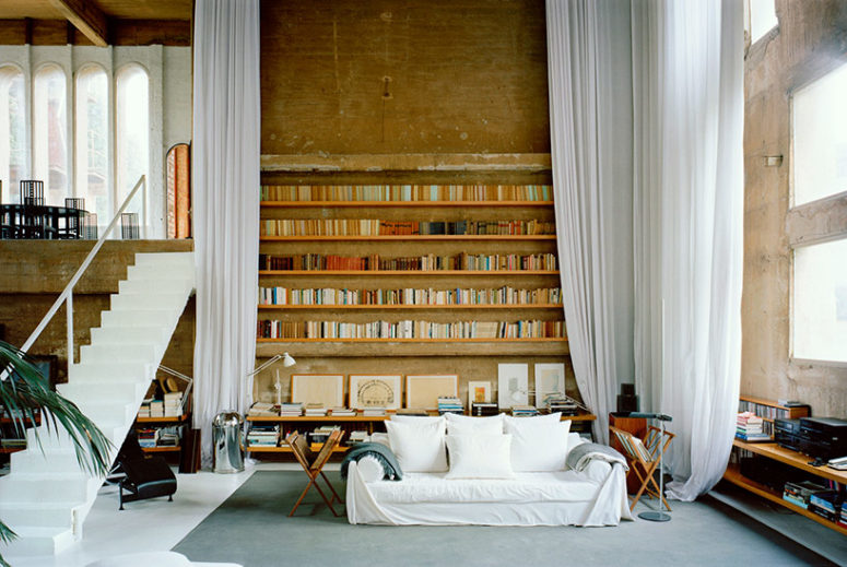 white curtains A seating area and library is tucked within a corner of the main factory space, creating a room with plenty of natural light and long curtains to section it of