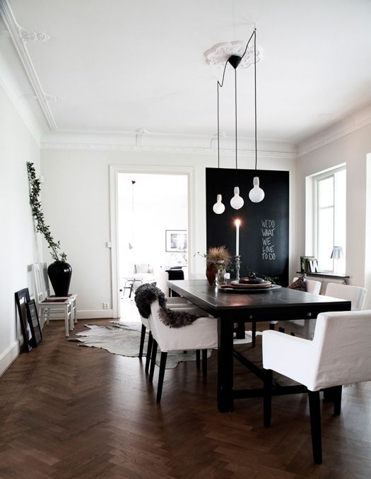 a simple black wooden table is accentuated with cool bulbs and white upholstered chairs