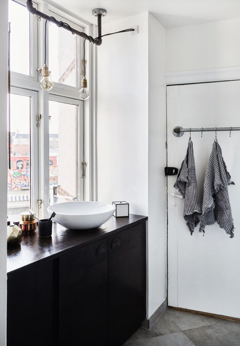 black cabinets in a bathroom The bathroom shows black cabinets, and the sink is right next to the window to save the space and enjoy the view