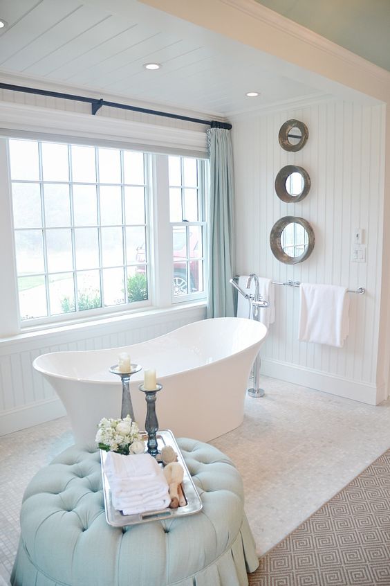 a modern soothing bathroom with aqua touches and a freestanding tub next to the window