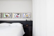 09 The bedroom features a dark colored bed and abstract artworks
