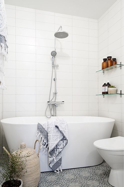 a very small bathroom with a patterned grey tile floor and a freestanding tub for a chic look