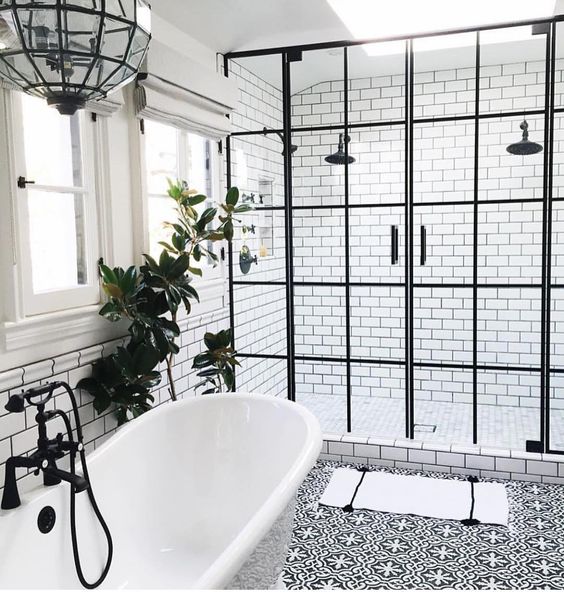 a freestanding tub is connected to the shower with a black faucet and a black glass pendant lamp over it