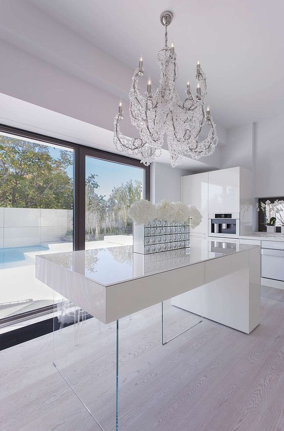 a minimalist white kitchen is spruced up with a modern crystal covered chandelier
