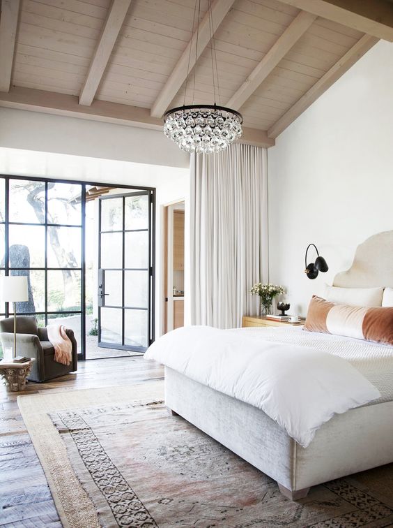 a modern bedroom with layered rugs and a chic crystal round chandelier of bubbles